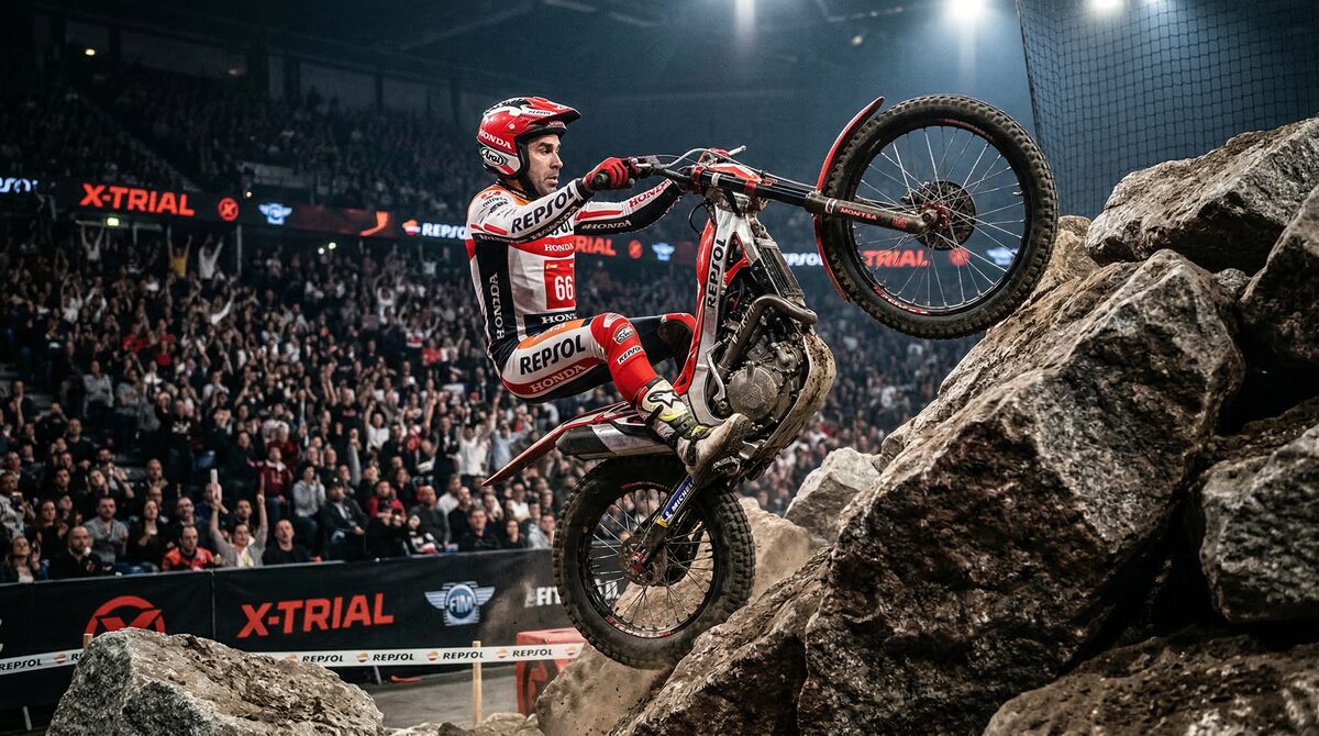 Motortrial rijder beklimt rotsen tijdens een indoor X-Trial competitie met publiek op de achtergrond